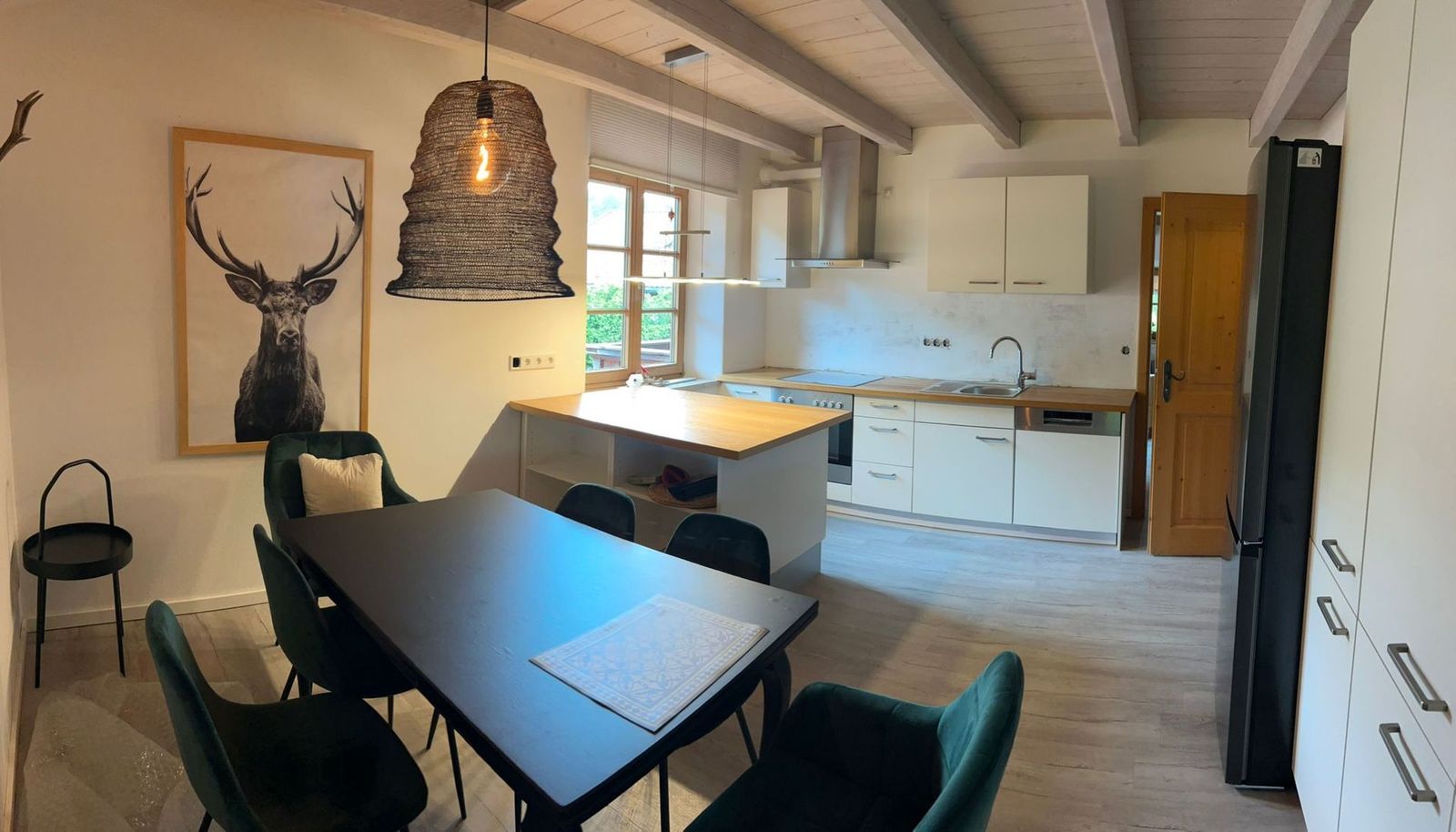 Essbereich der Ferienwohnung Bergblick mit großem Tisch, grünen Stühlen und offener Küche